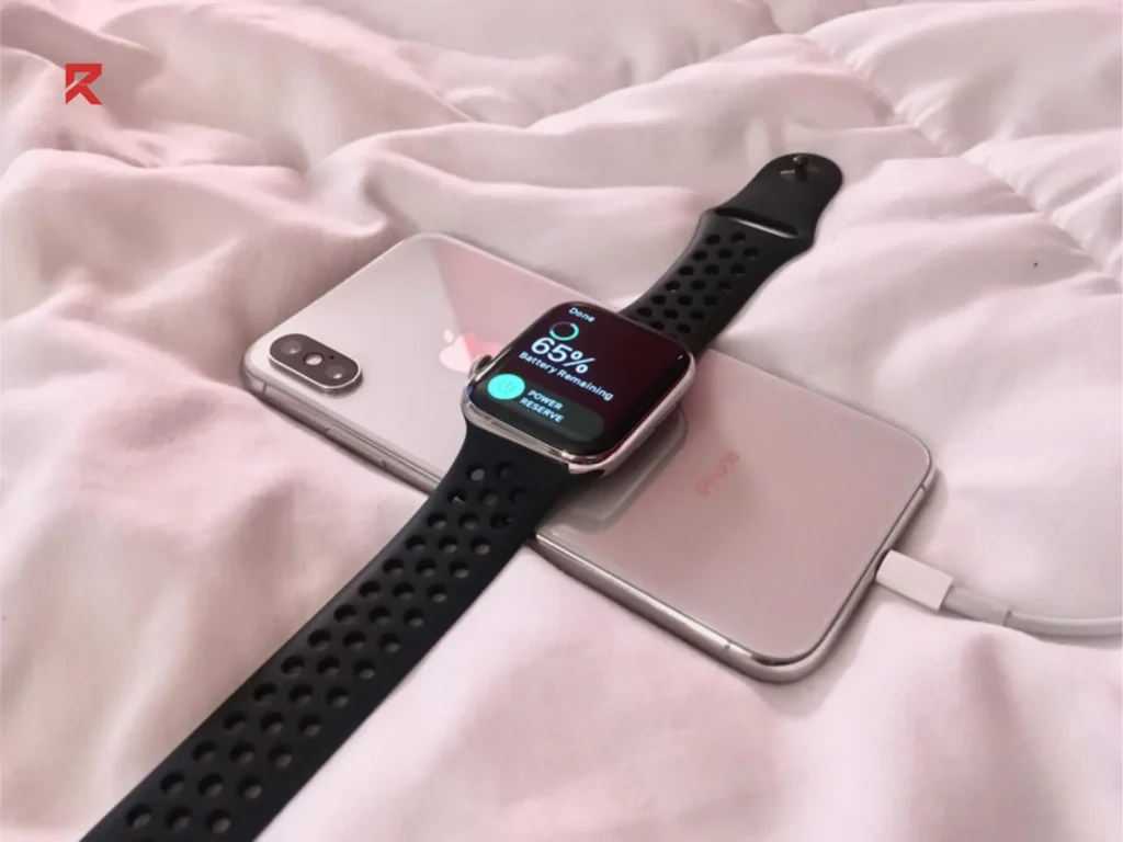 An apple watch is charging with the iPhone as Iphone is below the watch and charging the watch